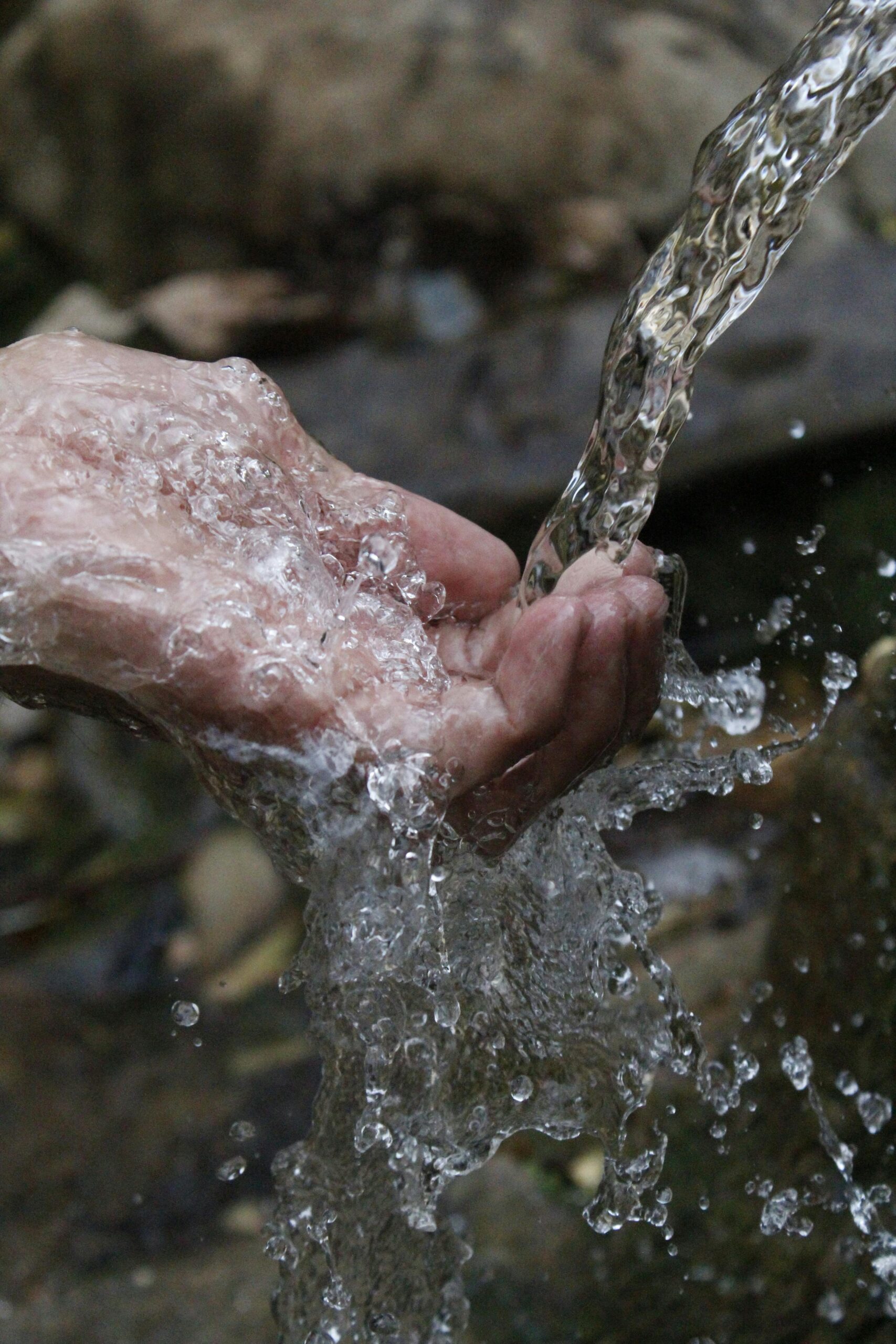 Close-up of a human hand under a stream of clear, flowing water.